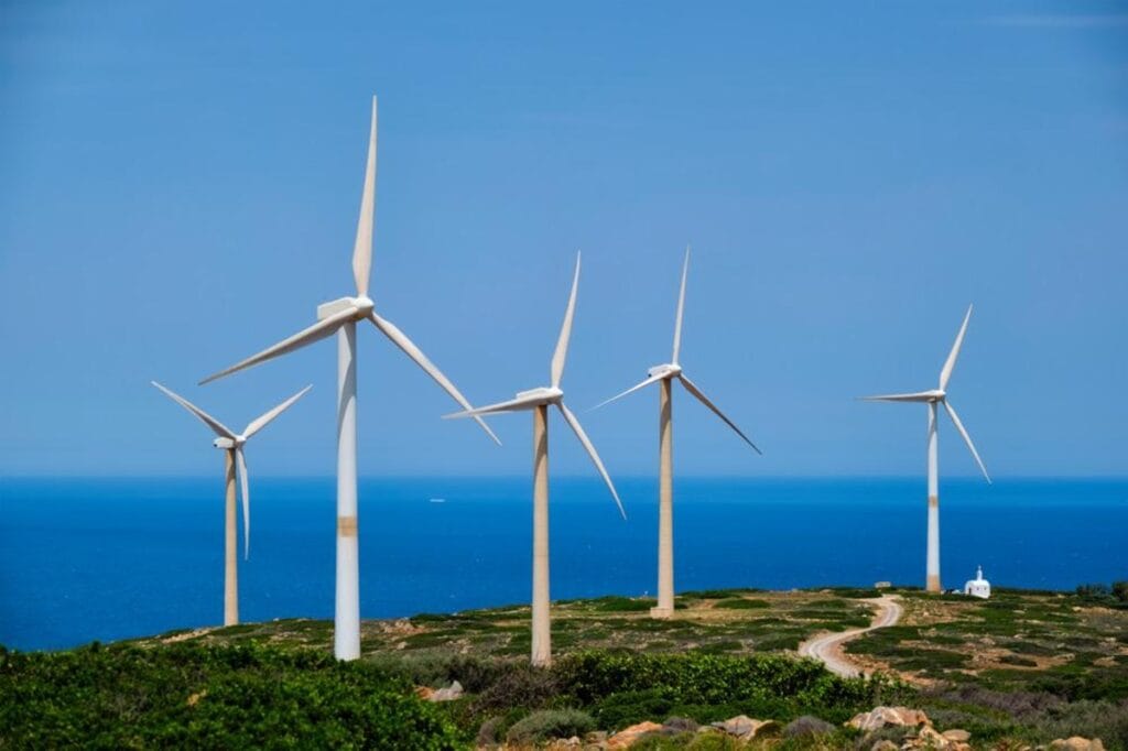 green renewable alternative energy concept wind generator turbines generating electricity wind farm crete island greece with small white church 01